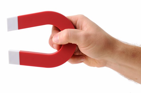 A hand holding a magnet isolated on white to pick up an object
